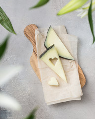 Wooden board with tasty goat cheese on concrete stone background. Cheese heart. Romantic holiday table setting. Beautiful background with blank. Restaurant concept.