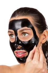 Portrait of young healthy woman with black peel face mask.