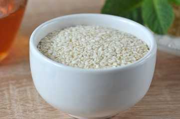 Sesame seeds in a white cup. Light background. Sesame seeds of white color. Close-up. Macro photography.