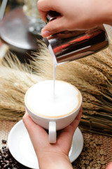 Close up pouring milk into coffee making hot latte - Soft focus