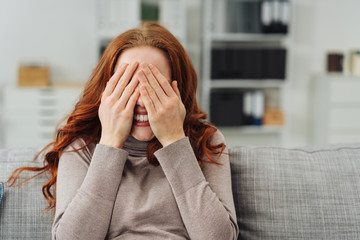 Young redhead woman covering her eyes