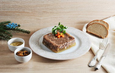 Jelly from beef meat. A dish of Russian cuisine called holodets. Next cups with mustard, a few slices of bread, cutlery. Light wooden background. Close-up.