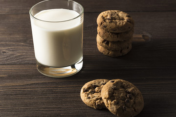  A glass of milk and cookies on a dark wooden background