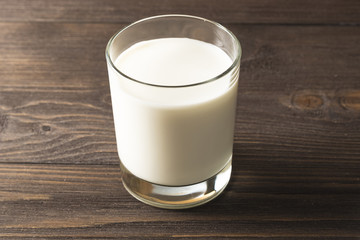 A glass of milk on a dark wooden background