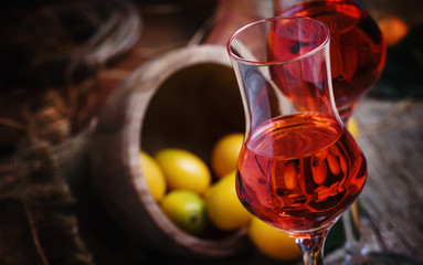 Traditional greek kumquat liqueur in shot glass, vintagen background, rustic style, selective focus