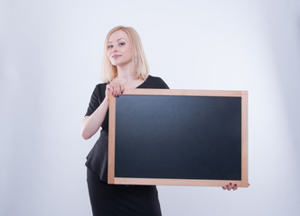 Close up of business woman with chalk board in black dress isolated on white background. Young blonde student girl holding black board. Place for text or message