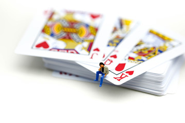 Miniature people : man sitting on Playing cards.
