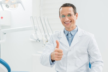 Dentist showing thumb up in modern dental clinic