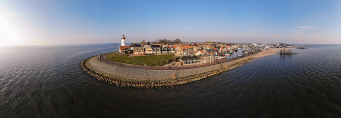 Lighthouse of urk on the rocky beach at the lake Ijsselmeer by the former island Urk Flevoland Netherlands, Bird eye view drone view of the old dutch village Urk - obrazy, fototapety, plakaty