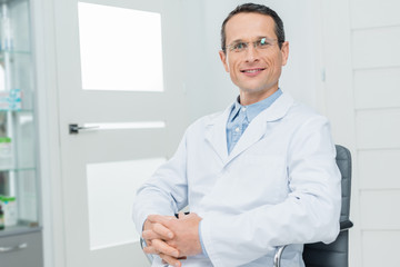 Fototapeta premium Smiling doctor with clenched hands in modern clinic