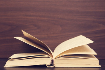 Book, diary, fanned pages on wooden deck table Back to school Education background