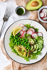 Mix salad with cucumber, avocado, green peas and flax seeds on a marble background