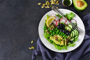 Vegan vegetable salad with flax seeds and olives on a black background