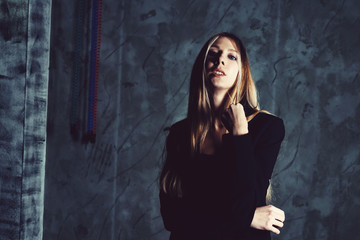 Fototapeta premium Attractive pretty young model posing against a dark studio background with copy space looking. Atomic blonde woman. Cold cinematic style