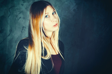 Fototapeta premium Attractive pretty young model posing against a dark studio background with copy space looking. Atomic blonde woman. Dramatic look