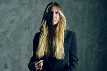 Attractive pretty young model posing against a dark studio background with copy space looking. Atomic blonde woman. Fashion style