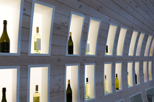 Wine Bottles On Wooden Shelf In Wine Store. Champagne In A Wooden Display Case