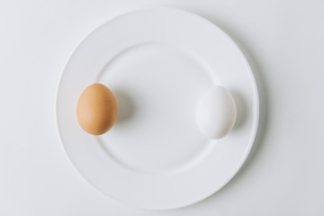 white and brown eggs laying on plate on white background