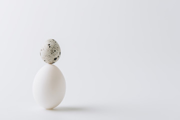 white egg and quail egg stacked on white background