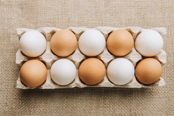 white and brown eggs laying in egg carton on sackcloth