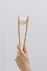 cropped image  of hand holding wooden tongs with white egg