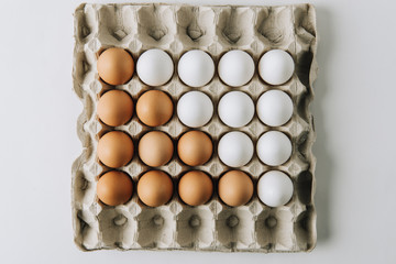 white and brown eggs laying in egg carton on white background