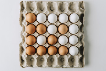 white and brown eggs laying in egg carton on white background