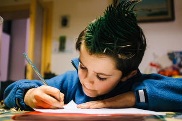 portrait of 9 year old boy at home with green colored hair crest performing school homework