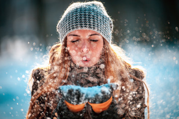 Naklejka premium Winter woman blowing snow outdoor at sunny day, flying snowflakes