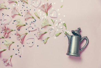 Magic spring appearance of flovers and hearts from vintage kettle on pink background. top view, flat lay. romantic spring picture
