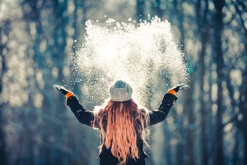 Foto op Plexiglas Young girl throwing snow in the air at sunny winter day, back view © leszekglasner