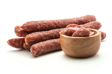 Hungarian dry sausages pepperoni pieces in a wooden bowl with separated stack isolated on white...