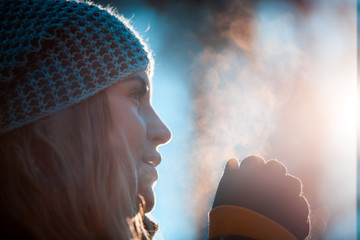 Woman breathing on her hands to keep them warm in cold winter day