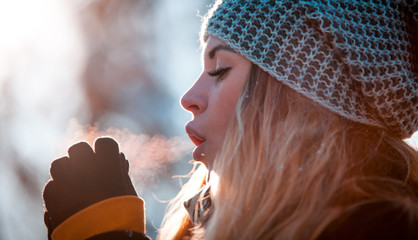 Woman breathing on her hands to keep them warm in cold winter day