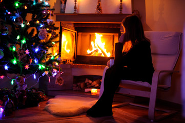 Obraz na płótnie Canvas Woman relaxing by the fire place, winter weekends, cozy scene