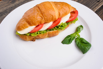 Fresh croissant with ham and salad
