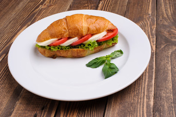 Fresh croissant with ham and salad
