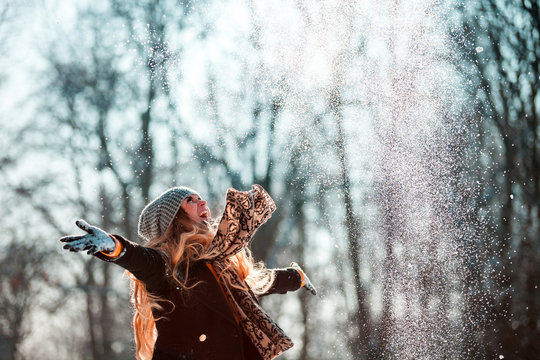Smiling woman throwing snow in the air at sunny winter day © leszekglasner