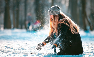 Fototapeta premium Smiling woman throwing snow in the air at sunny winter day