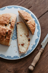 Freshly baked traditional German Easter Bread, Osterbrot, made of Brioche yeast dough with raisins and butter sliced on floral cake plate served as breakfast for Easter Sunday on wooden background