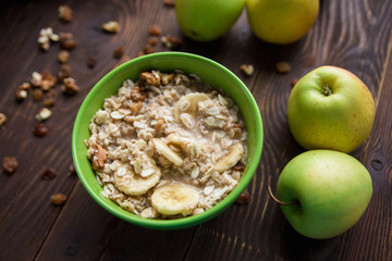 oatmeal with fruit and dried fruits.bananas,apples.wooden table.healthy organic food concept.