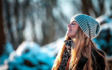 Fototapeta premium Young woman in the winter park at sunny day, warm clothes