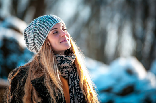 Young woman in the winter park at sunny day, warm clothes - Powered by Adobe