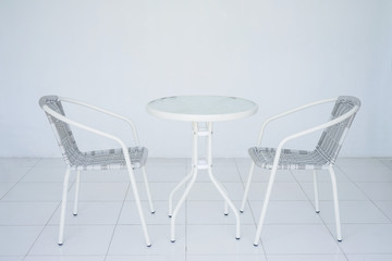 Transparent white table in the cafe. Two Rattan chair in the background. The whole room is white. Side view with copy space