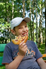 Hungry boy eating pizza outdoor