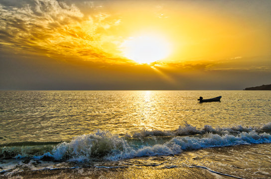 Fototapeta Lonely boat during sunrise and an orange sky