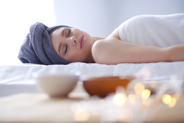 Young woman lying on a massage table,relaxing with eyes closed. Woman. Spa salon