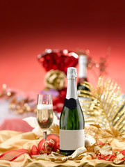 champagne bottle with blank label and flute on a table set for Christmas party. red and golden background