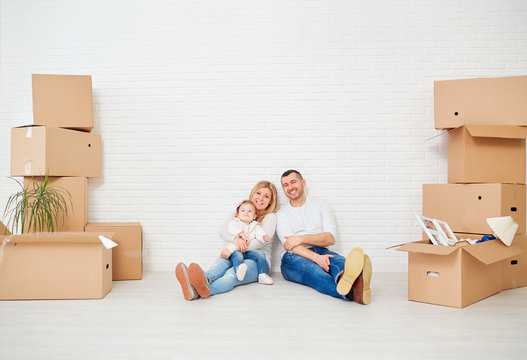 A family with boxes moves to a new house against a white wall. Property For Sale.