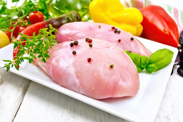 Chicken breast raw in plate with vegetables on table
